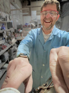 John Schiff, founder of GiveSurplus, working with electronics equipment in a workshop in Southern Idaho.